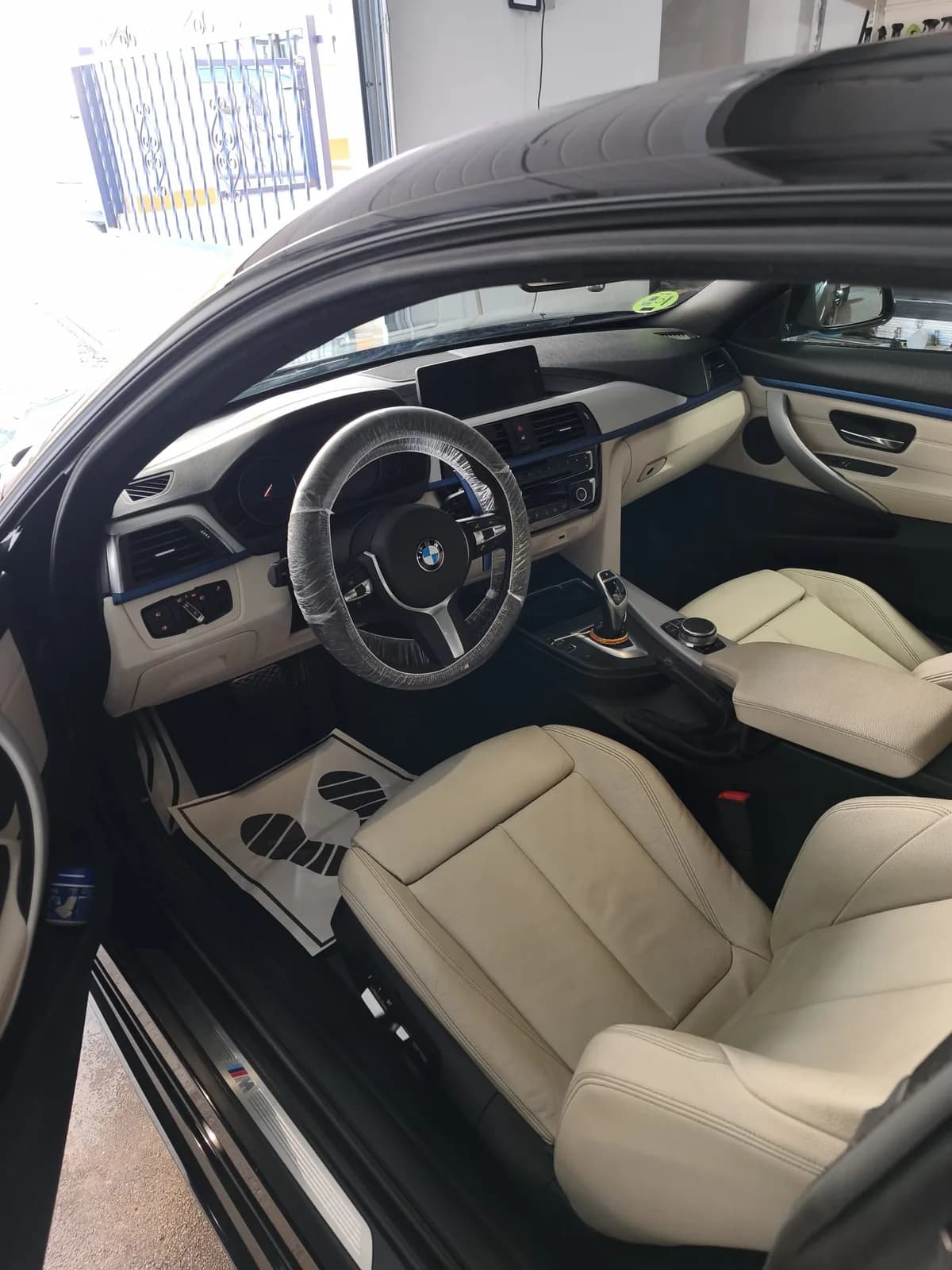 Interior en cuero crema del BMW 440i con el volante protegido tras el detallado