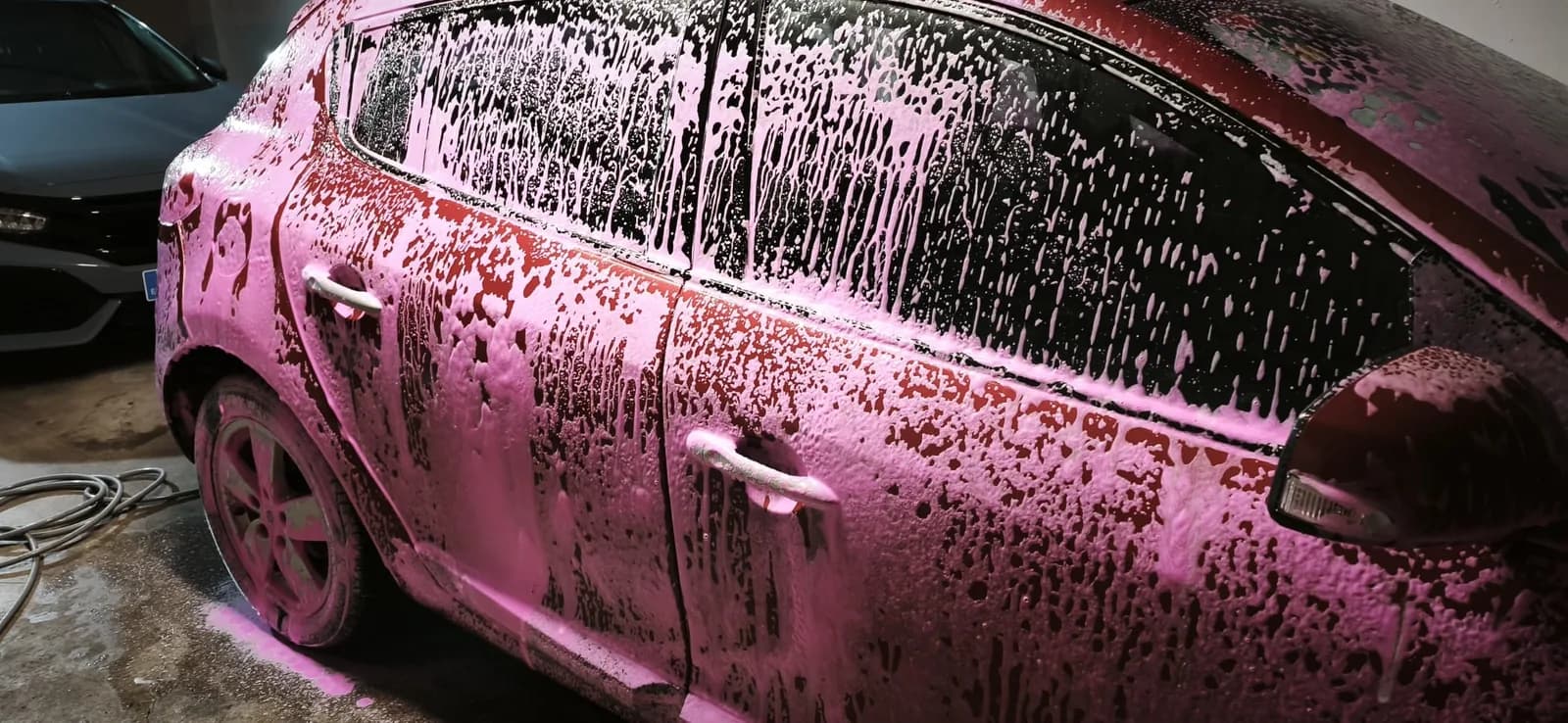 Lateral de un coche cubierto de espuma activa durante el lavado de detalle